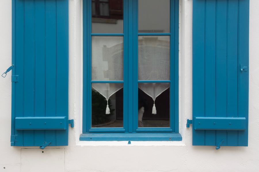 Fenêtre bleue à volets bleus ouverts sur un mur blanc à la chaux